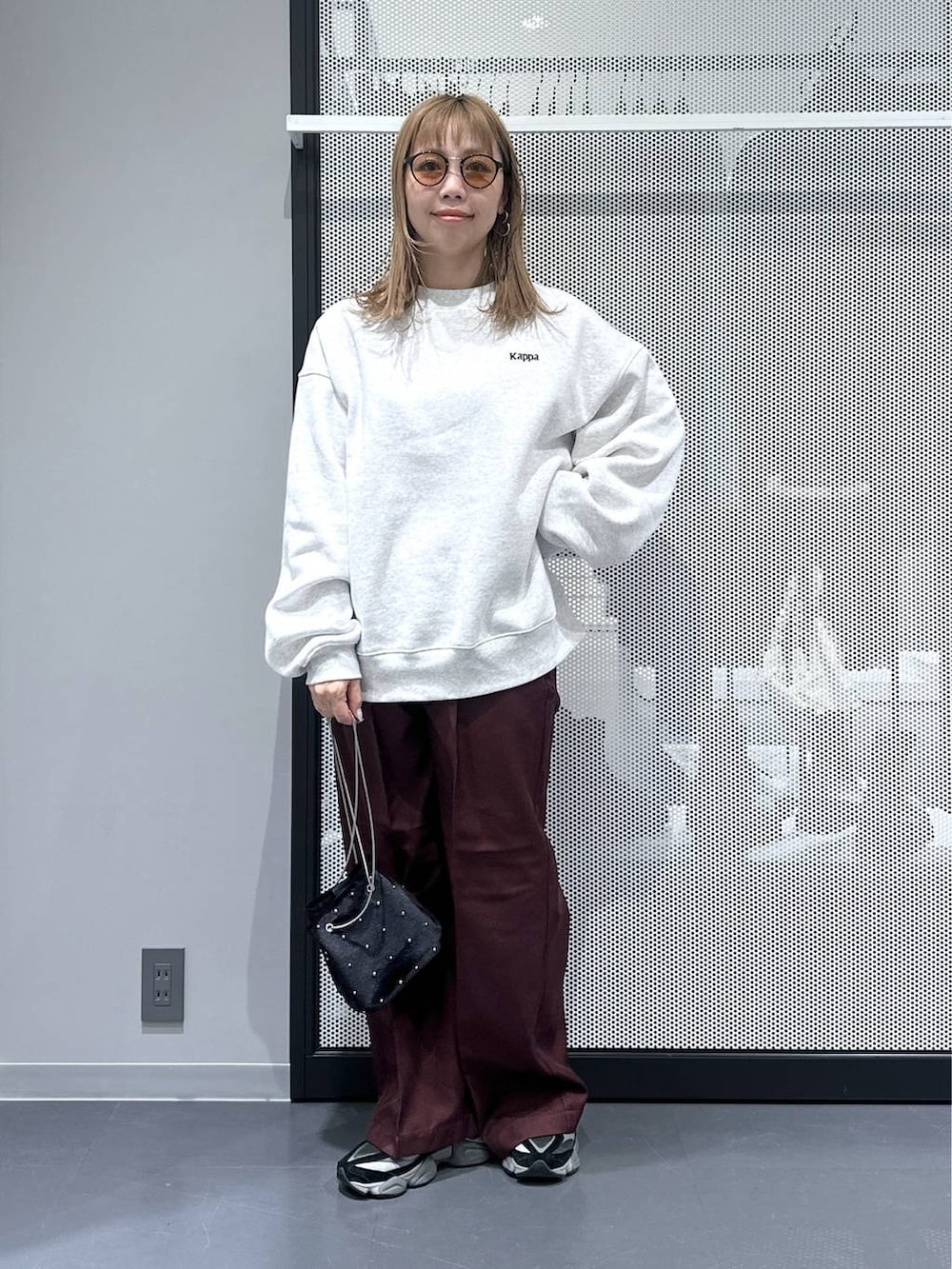 グレー系のベスト、ブラック系のショルダーバッグ、レッド系のスラックスを着用したレディースの秋コーディネートの6枚目の写真