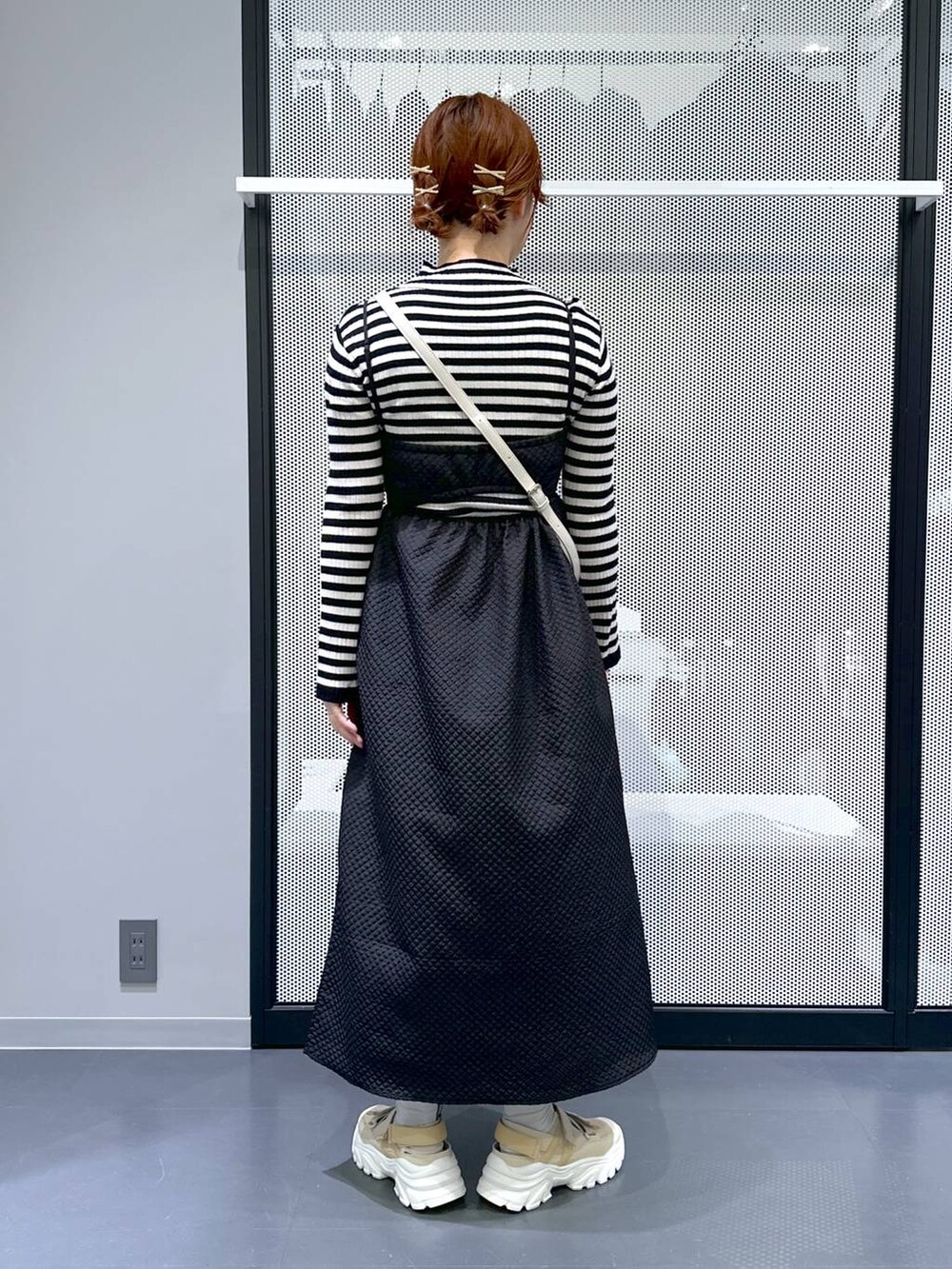 ベージュ系のスニーカー、ブラック系のワンピース、ホワイト系のショルダーバッグを着用したレディースの冬コーディネートの2枚目の写真