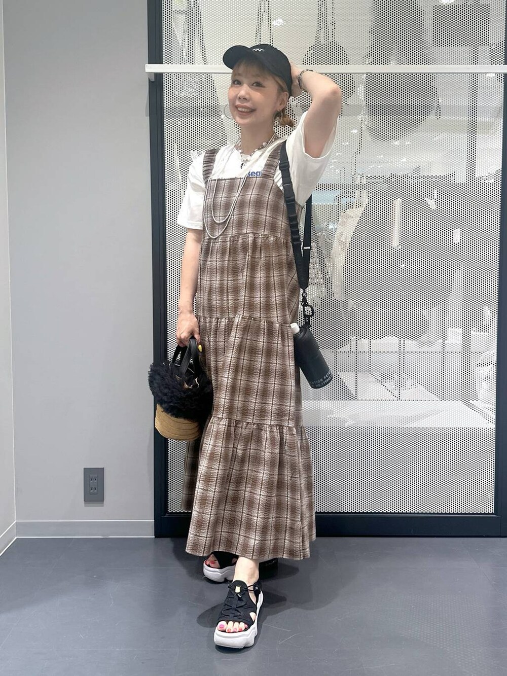 ベージュ系のショルダーバッグ、ブラウン系のワンピース、ブラック系のサンダルを着用したレディースの春コーディネートの4枚目の写真