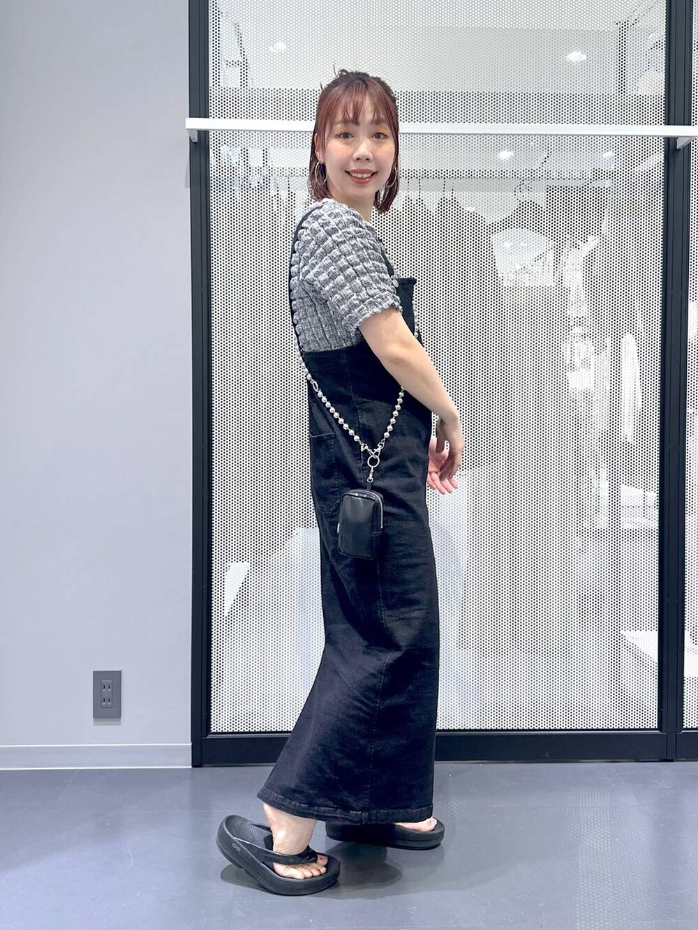 グレー系のジャンパースカート、ブラック系のサンダル、その他のTシャツ/カットソーを着用したレディースの夏コーディネートの4枚目の写真