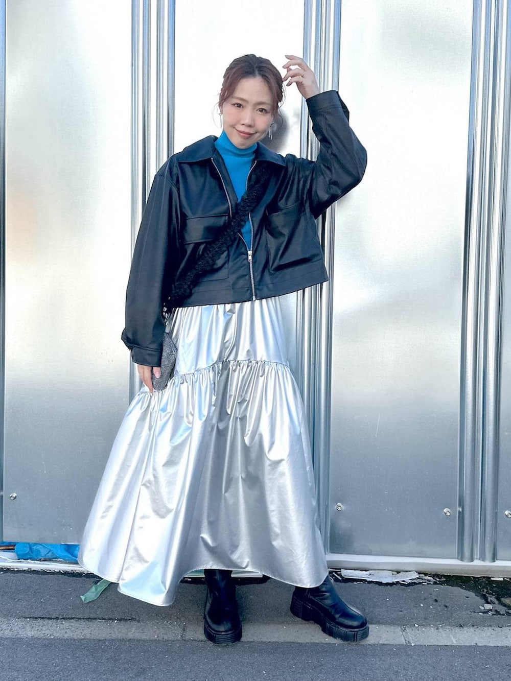 ブラック系のブルゾン、シルバー系のスカート、ブルー系のニット/セーターを着用したレディースの冬コーディネートの2枚目の写真