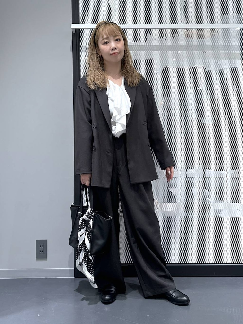 ブラック系のトートバッグ、グレー系のスラックス、ブラック系のローファーを着用したレディースの春コーディネートの2枚目の写真