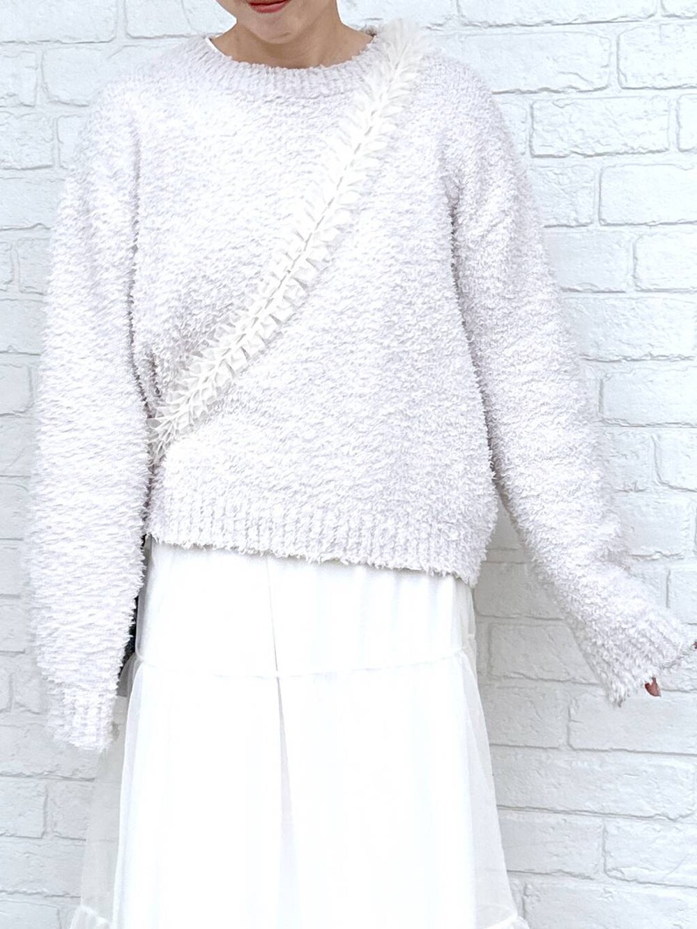 グレー系のニット/セーター、ホワイト系のブーツ、ホワイト系のTシャツ/カットソーを着用したレディースの冬コーディネートの4枚目の写真