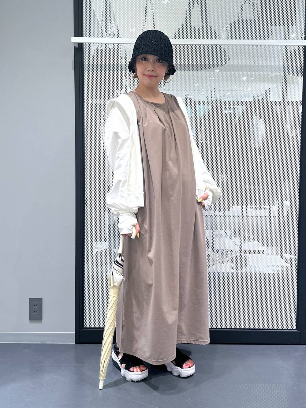 ブラウン系のワンピース、ブラック系のサンダル、ベージュ系の長傘を着用したレディースの春コーディネートの7枚目の写真