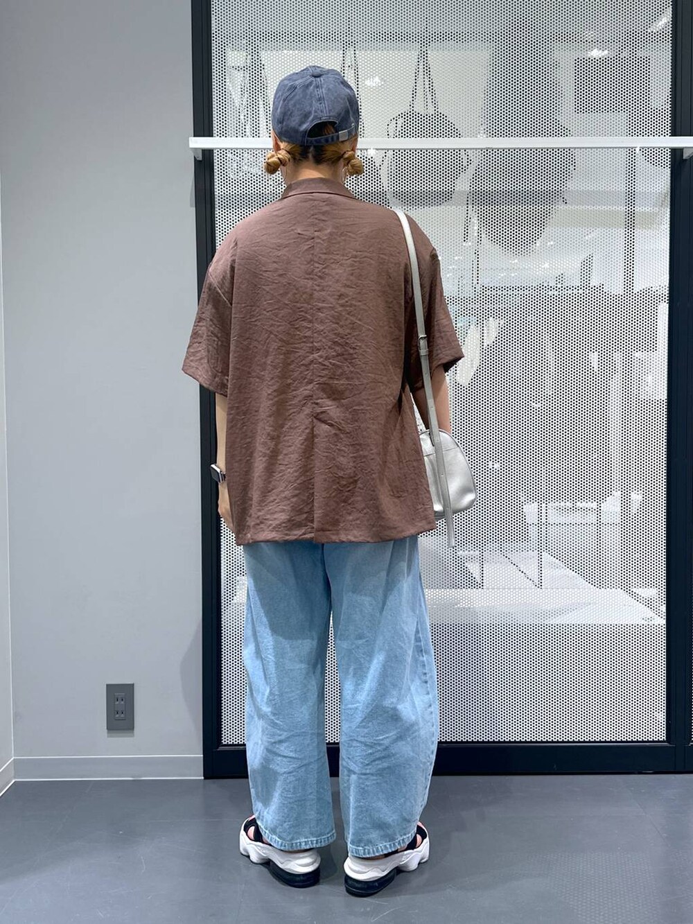 ブルー系のデニムパンツ、シルバー系のショルダーバッグ、ホワイト系のベストを着用したレディースの夏コーディネートの3枚目の写真