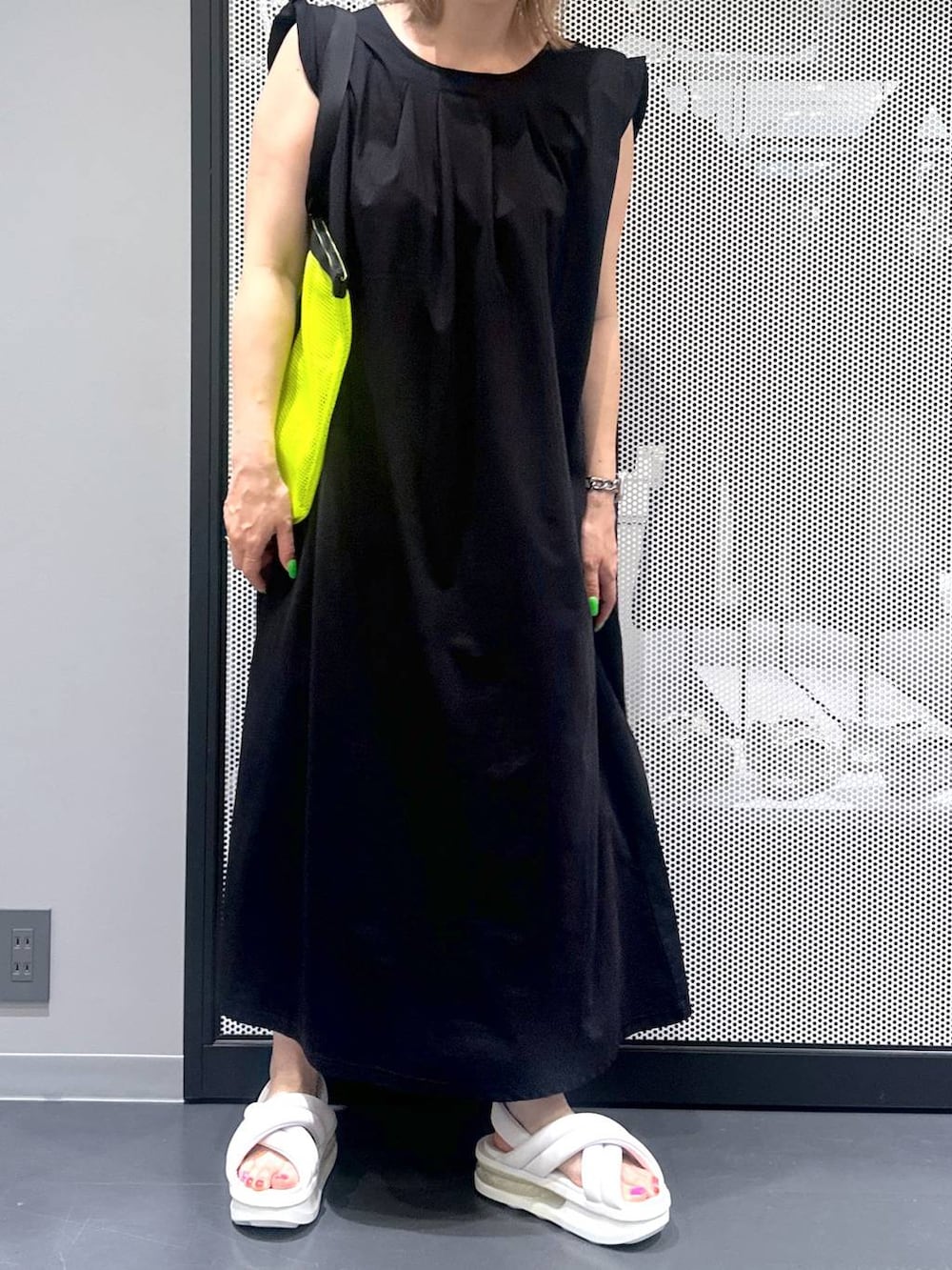 ブラック系のワンピース、イエロー系のトートバッグ、ホワイト系のサンダルを着用したレディースの春コーディネートの4枚目の写真