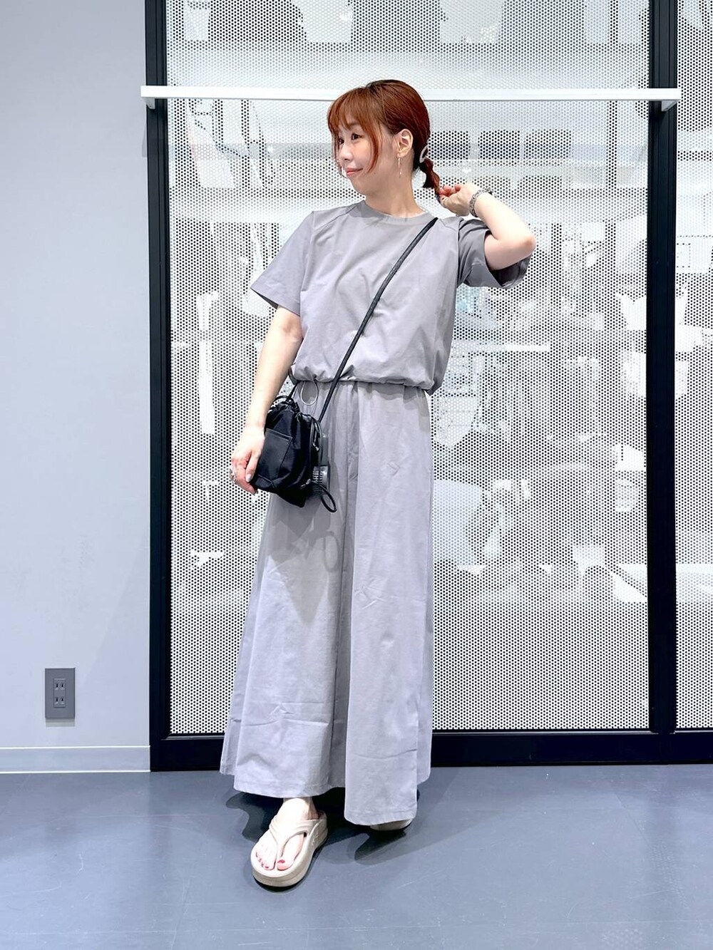 ブラック系のショルダーバッグ、ベージュ系のサンダル、グレー系のTシャツ/カットソーを着用したレディースの夏コーディネートの2枚目の写真