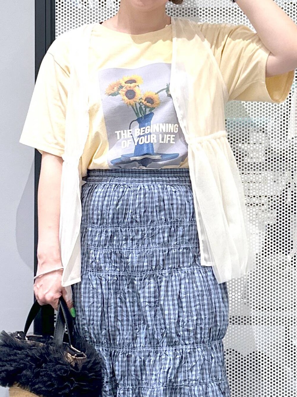 ベージュ系のショルダーバッグ、イエロー系のTシャツ/カットソー、ブルー系のスカートを着用したレディースの春コーディネートの5枚目の写真