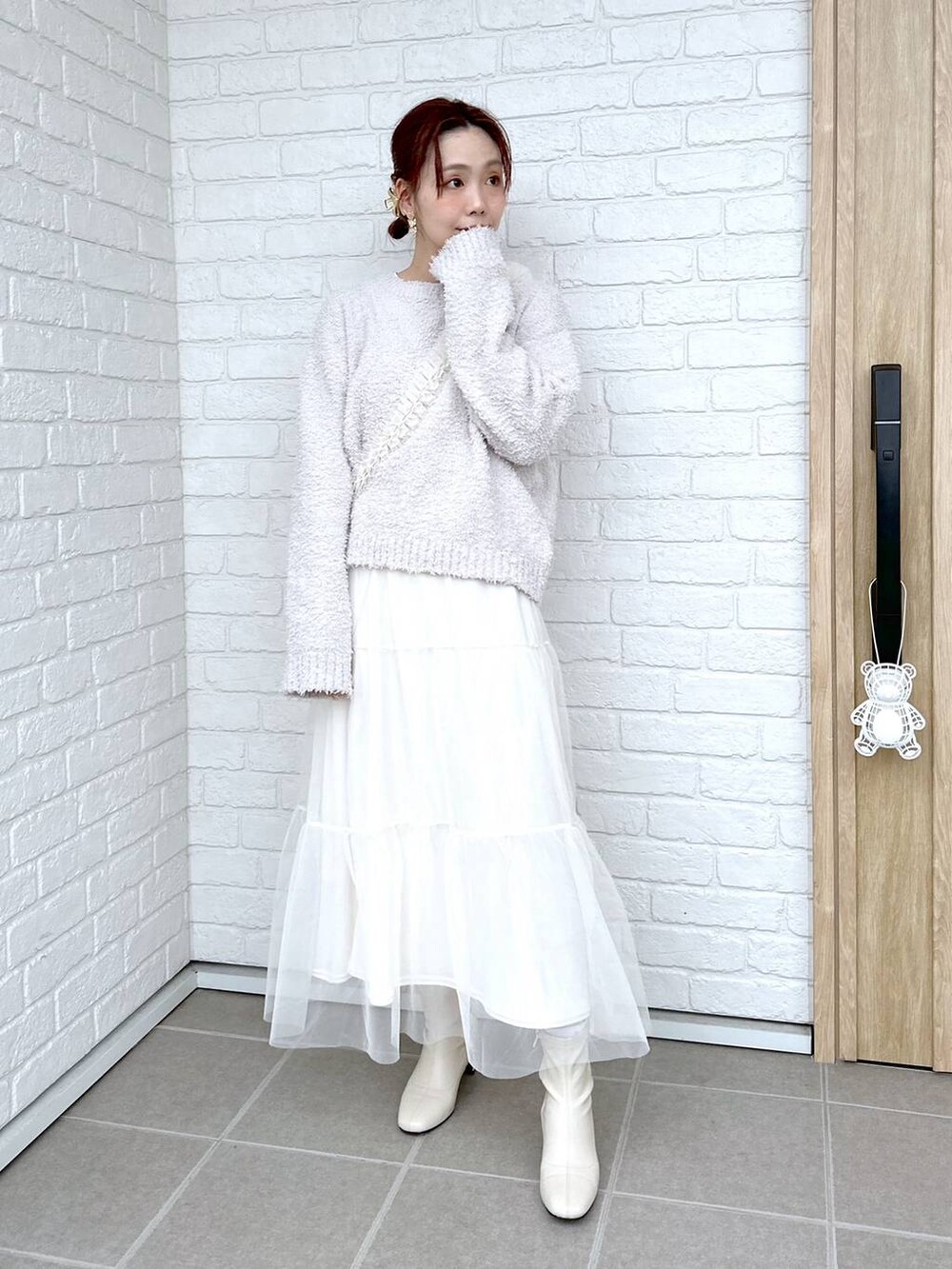 グレー系のニット/セーター、ホワイト系のブーツ、ホワイト系のTシャツ/カットソーを着用したレディースの冬コーディネートの2枚目の写真