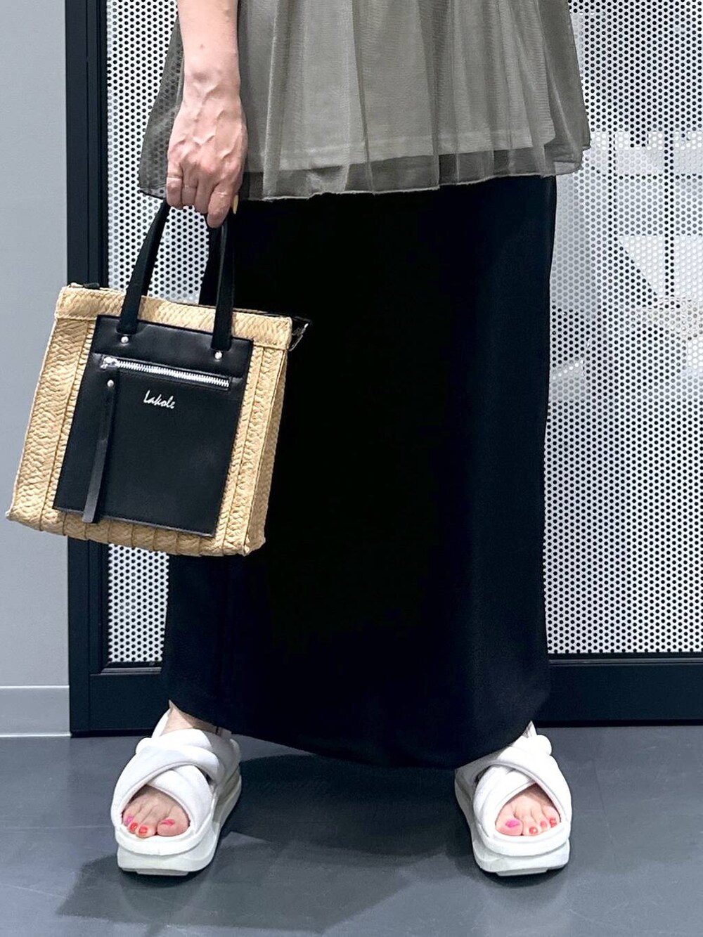 ベージュ系のショルダーバッグ、ブラック系のスカート、グリーン系のTシャツ/カットソーを着用したレディースの春コーディネートの4枚目の写真