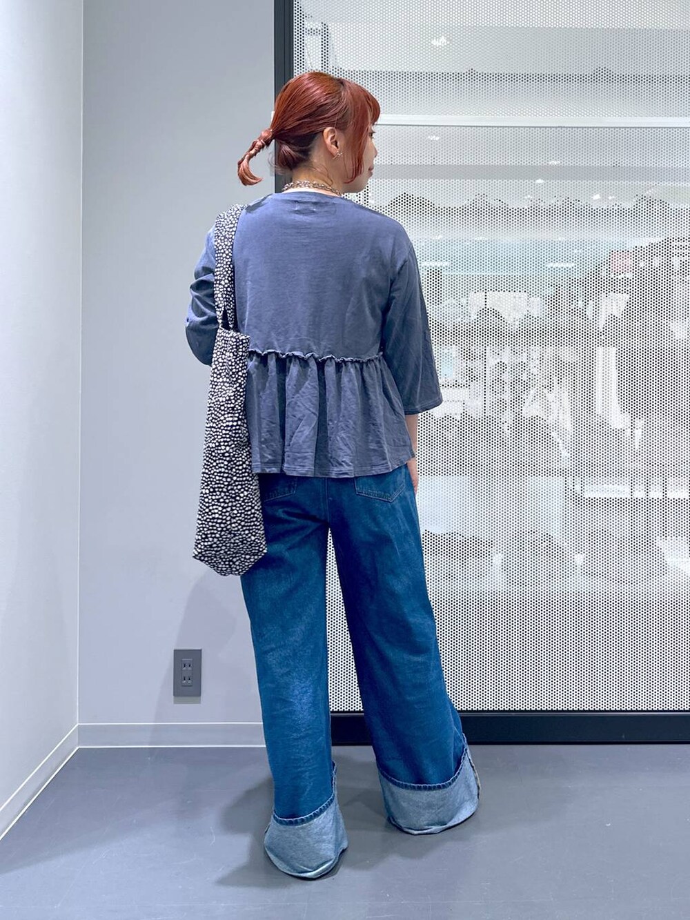 ブラック系のトートバッグ、シルバー系のパンプス、ブルー系のデニムパンツを着用したレディースの夏コーディネートの4枚目の写真