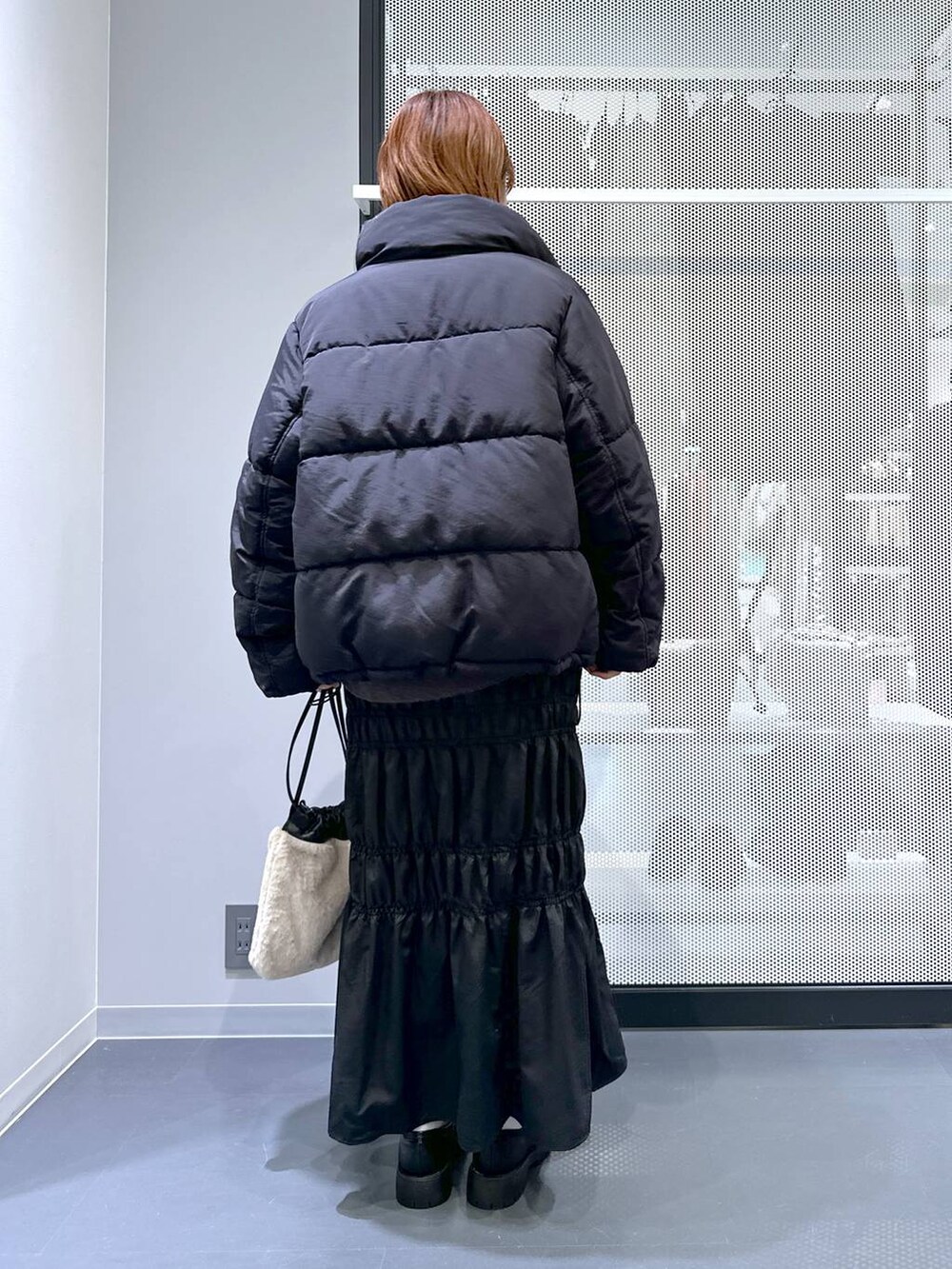 グレー系のニット/セーター、ブラック系のナイロンジャケット、ベージュ系のショルダーバッグを着用したレディースの冬コーディネートの3枚目の写真