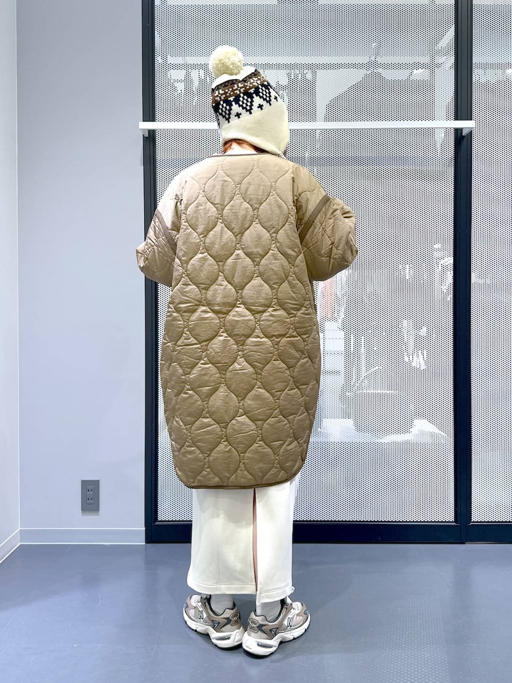 ブラウン系のスニーカー、ベージュ系のショルダーバッグ、グリーン系のナイロンジャケットを着用したレディースの冬コーディネートの4枚目の写真