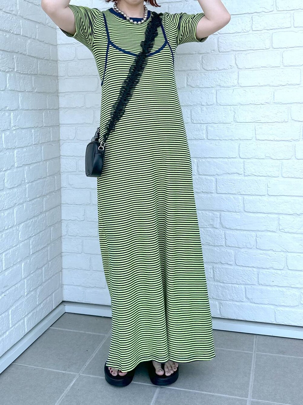 グリーン系のワンピース、ブラック系のサンダル、ブラック系のポーチを着用したレディースの春コーディネートの6枚目の写真