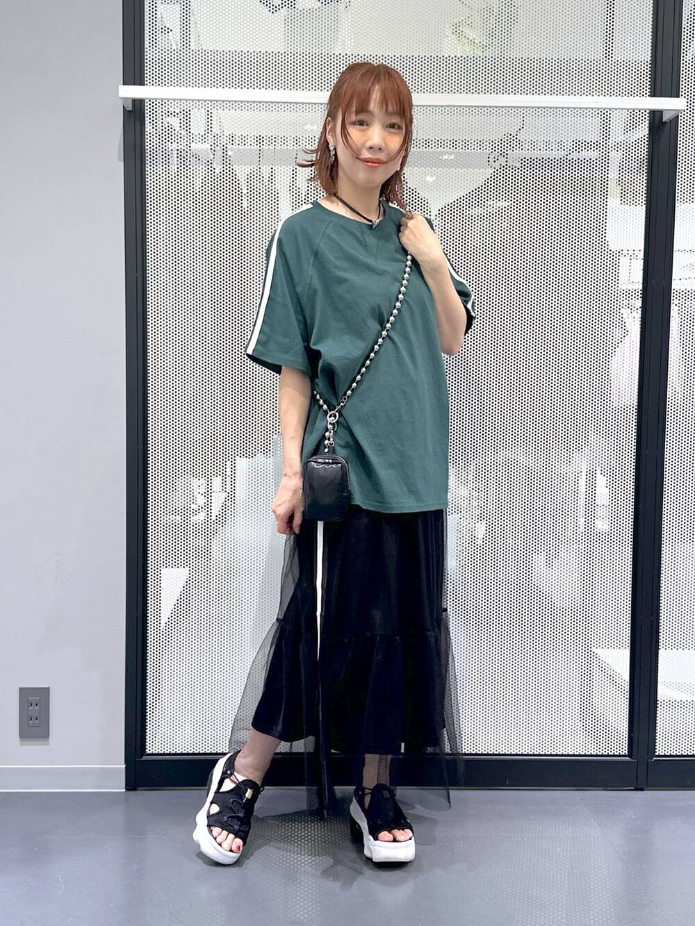 ブラック系のスカート、グリーン系のTシャツ/カットソー、その他のネックレスを着用したレディースの夏コーディネートの6枚目の写真