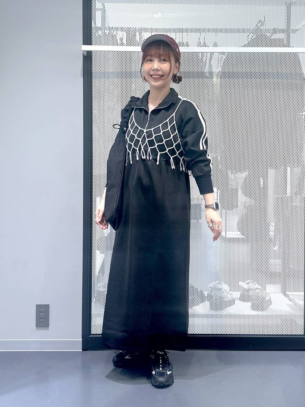 グレー系のスニーカー、ホワイト系のベスト、ブラック系のショルダーバッグを着用したレディースの秋コーディネートの2枚目の写真