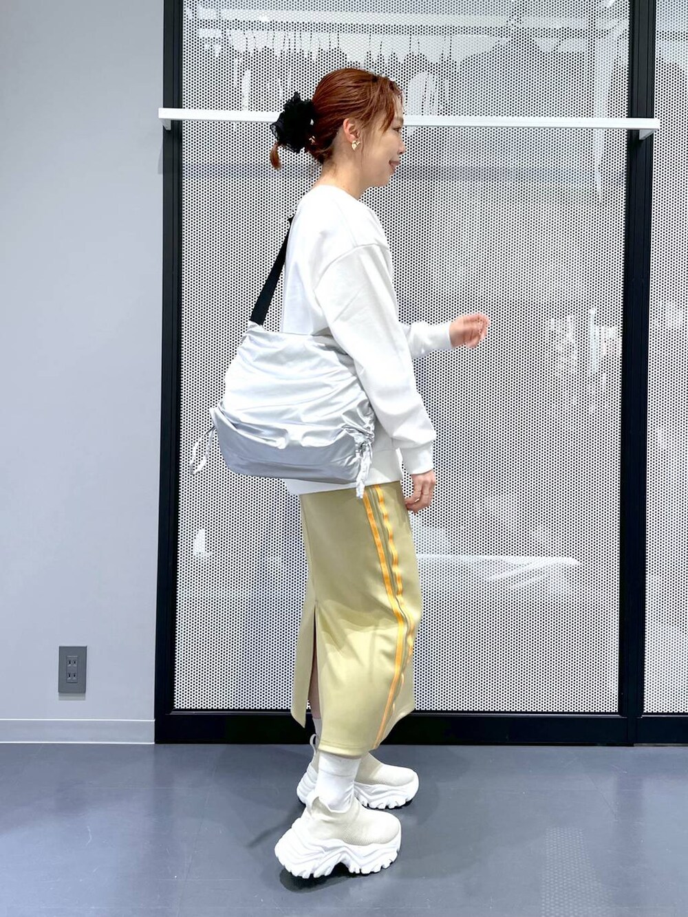 グリーン系のスカート、シルバー系のショルダーバッグ、ブラック系のシュシュを着用したレディースの冬コーディネートの3枚目の写真