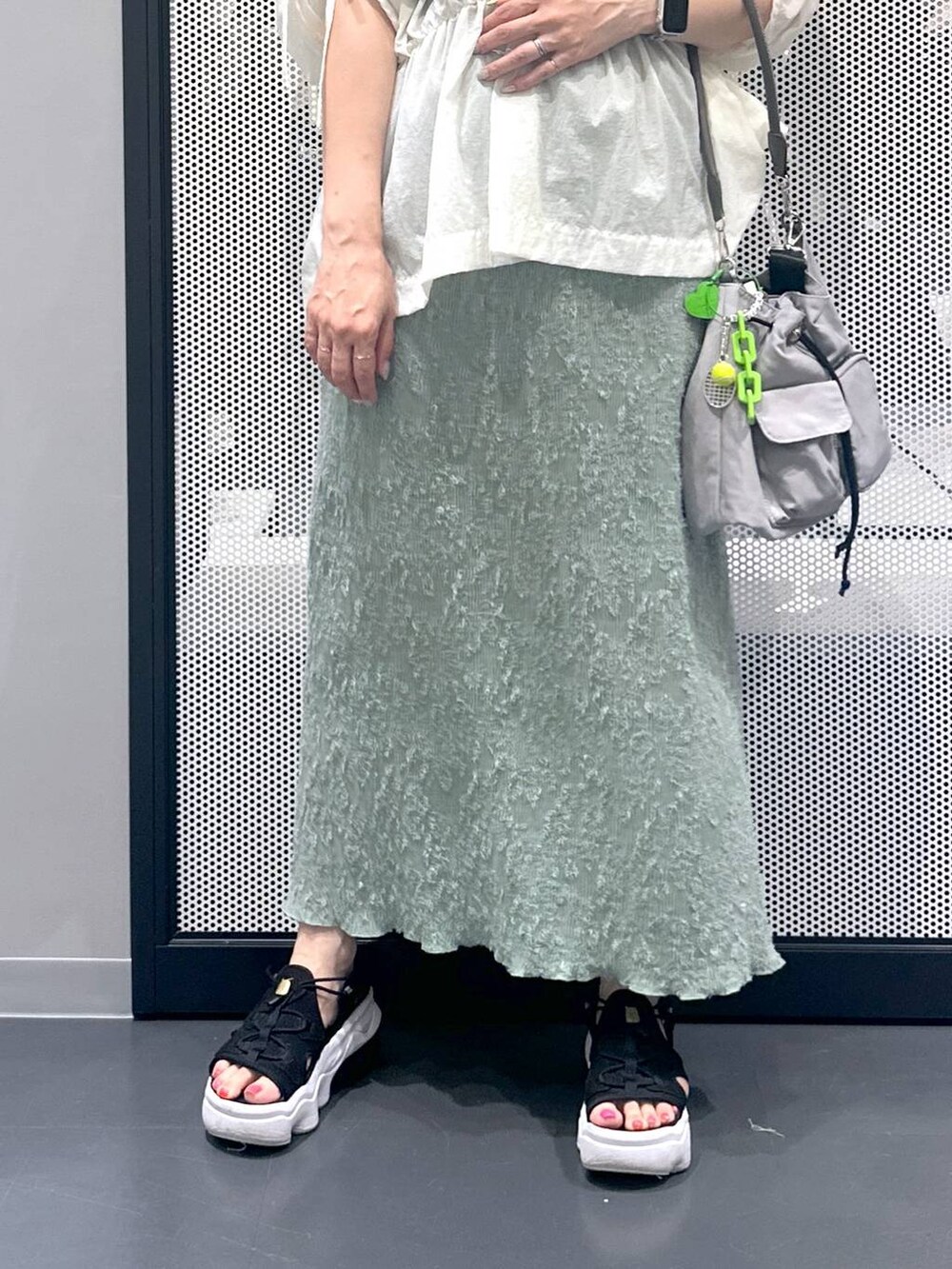 ブラック系のタンクトップ、グレー系のショルダーバッグ、グリーン系のスカートを着用したレディースの夏コーディネートの5枚目の写真