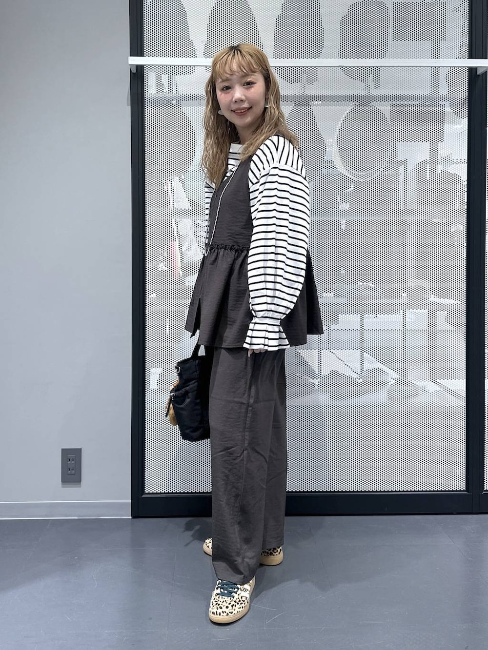 グレー系のその他パンツ、ブラック系のトートバッグ、ベージュ系のスニーカーを着用したレディースの春コーディネートの2枚目の写真