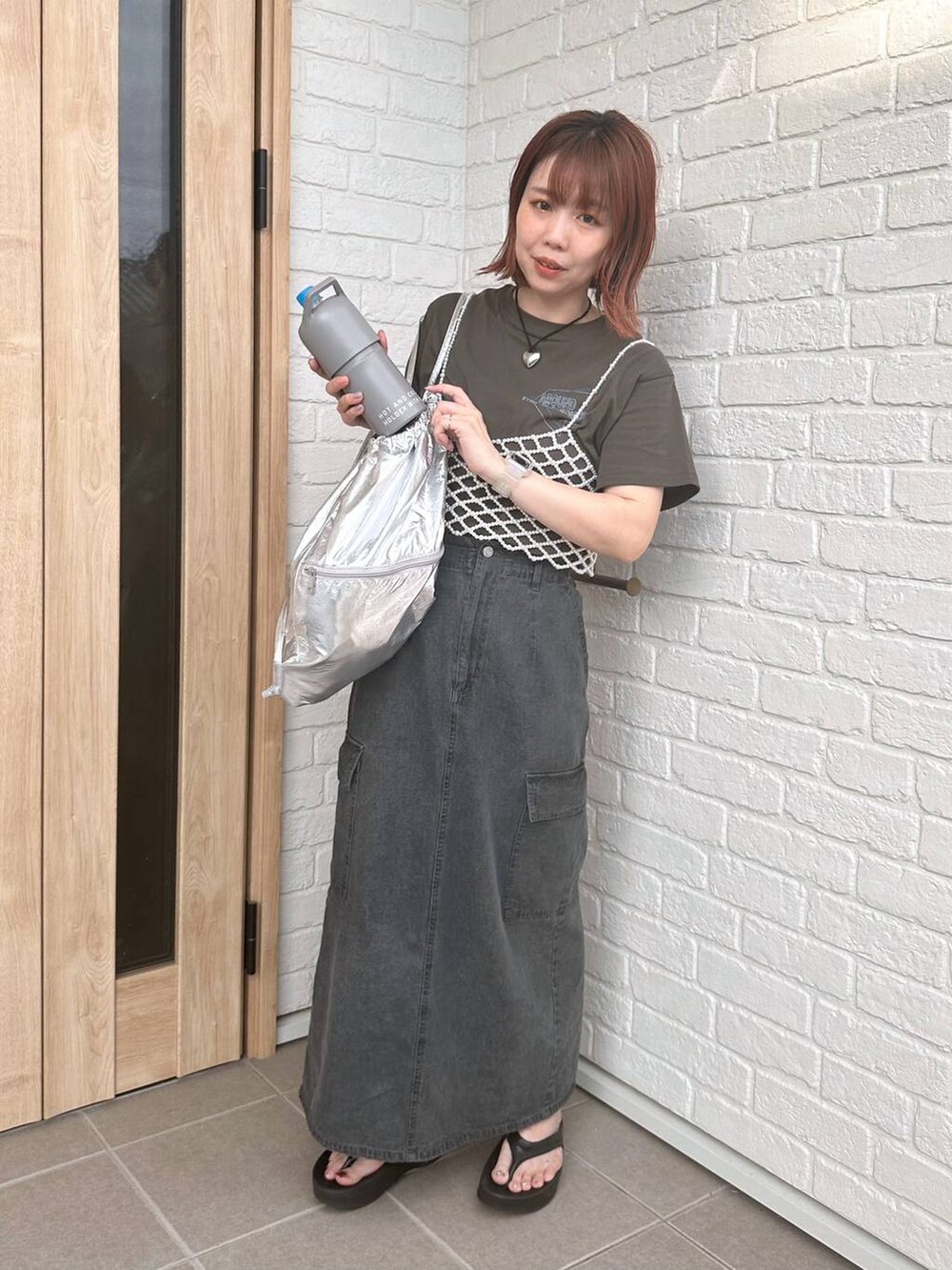 グレー系のデニムスカート、シルバー系のバックパック/リュック、ブラック系のサンダルを着用したレディースの春コーディネートの5枚目の写真