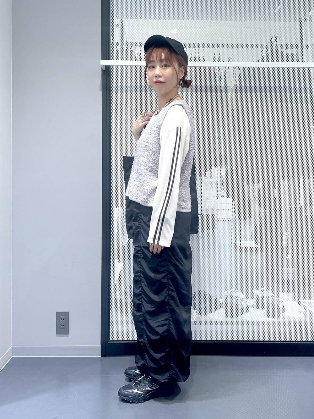 グレー系のスニーカー、ホワイト系のTシャツ/カットソー、グレー系のベストを着用したレディースの秋コーディネートの3枚目の写真