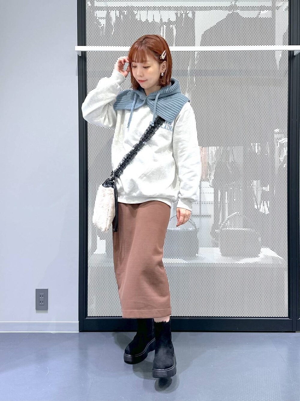 ベージュ系のショルダーバッグ、ブラウン系のスカート、ブラック系のブーツを着用したレディースの冬コーディネートの2枚目の写真