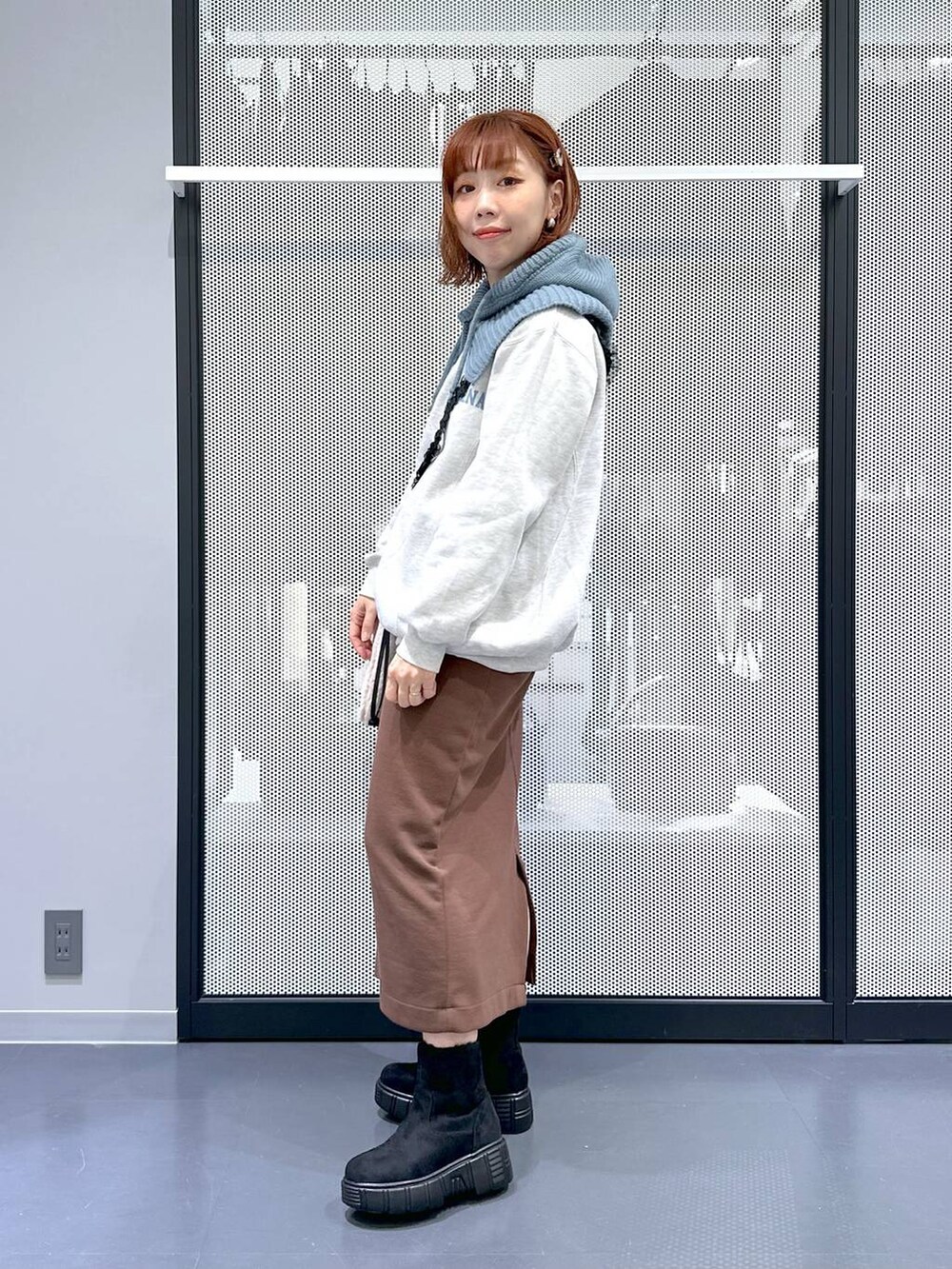 ベージュ系のショルダーバッグ、ブラウン系のスカート、ブラック系のブーツを着用したレディースの冬コーディネートの3枚目の写真