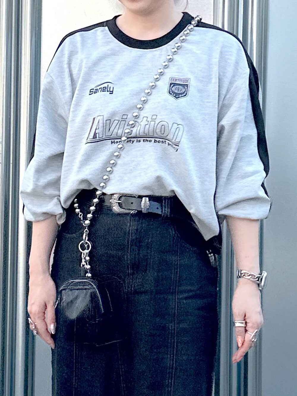 ブラック系のデニムスカート、グレー系のTシャツ/カットソー、ブラック系のブーツを着用したレディースの秋コーディネートの7枚目の写真