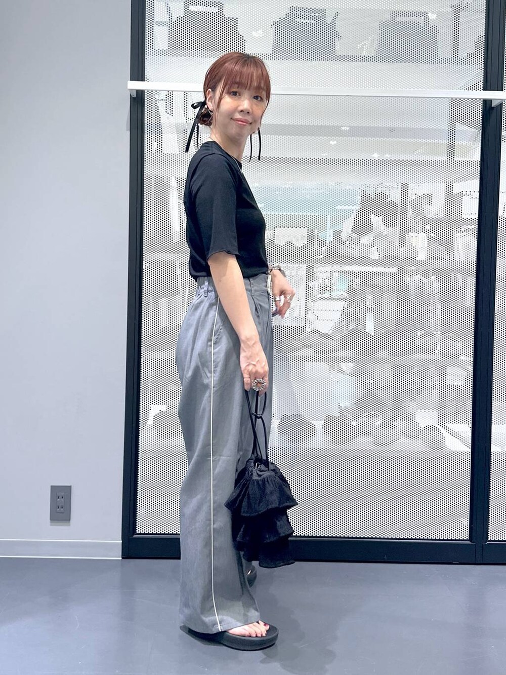 ブラック系のTシャツ/カットソー、グレー系のスラックス、ブラック系のサンダルを着用したレディースの夏コーディネートの3枚目の写真