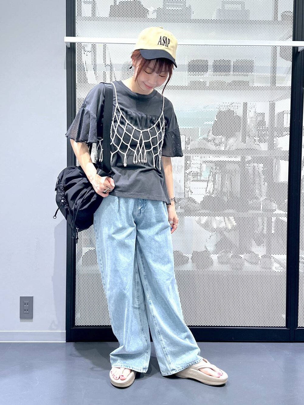 ブラック系のショルダーバッグ、ブルー系のデニムパンツ、ホワイト系のベストを着用したレディースの夏コーディネートの5枚目の写真