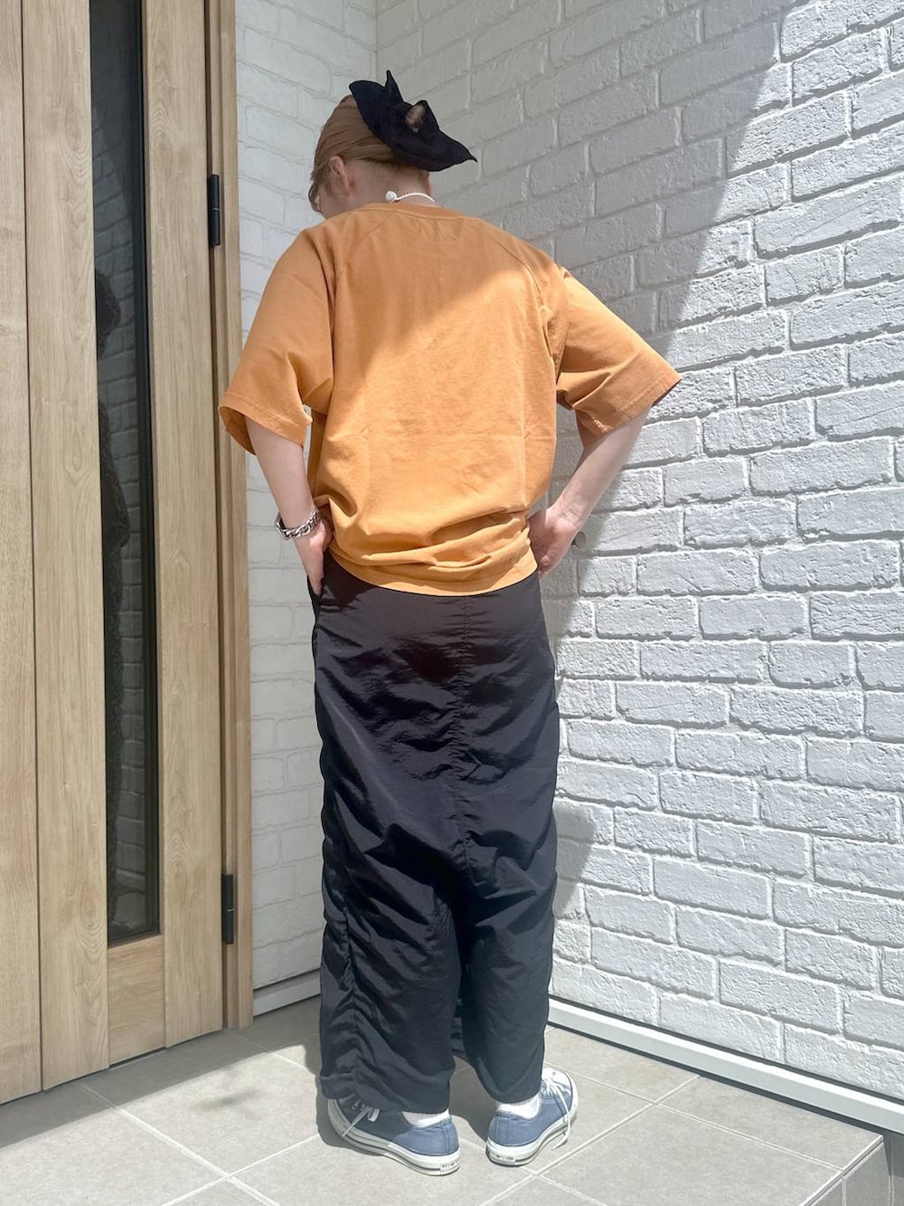 ブラック系のスカート、オレンジ系のTシャツ/カットソー、シルバー系のデジタル腕時計を着用したレディースの春コーディネートの2枚目の写真