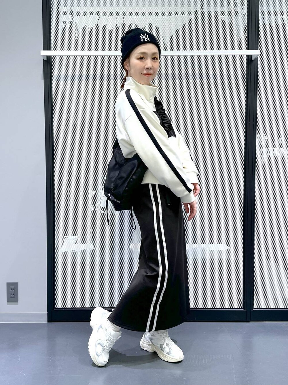 ブラック系のスカート、ベージュ系のブルゾン、ホワイト系のスニーカーを着用したレディースの冬コーディネートの3枚目の写真