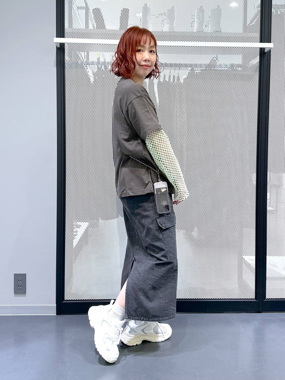 グレー系のデニムスカート、グリーン系のTシャツ/カットソー、ホワイト系のスニーカーを着用したレディースの春コーディネートの3枚目の写真