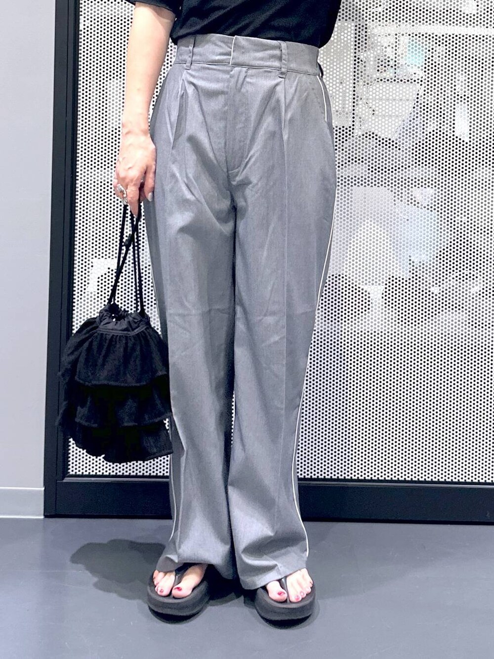 ブラック系のTシャツ/カットソー、グレー系のスラックス、ブラック系のサンダルを着用したレディースの夏コーディネートの5枚目の写真