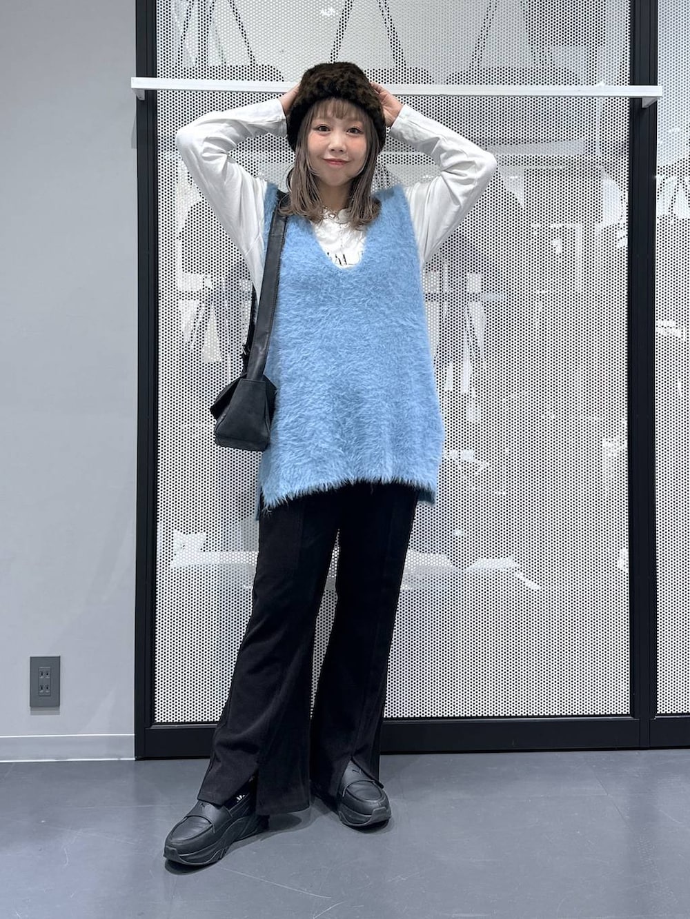 ブラック系のショルダーバッグ、ブルー系のベスト、ホワイト系のTシャツ/カットソーを着用したレディースの秋コーディネートの2枚目の写真