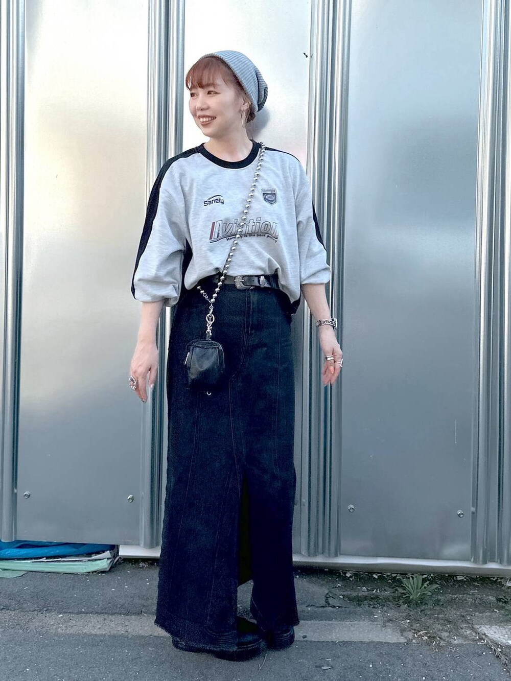 ブラック系のデニムスカート、グレー系のTシャツ/カットソー、ブラック系のブーツを着用したレディースの秋コーディネートの2枚目の写真