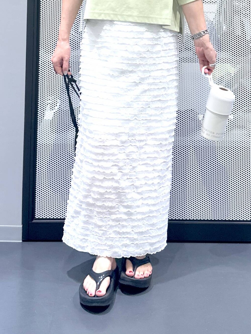 ブラック系のショルダーバッグ、ホワイト系のスカート、グリーン系のTシャツ/カットソーを着用したレディースの夏コーディネートの7枚目の写真