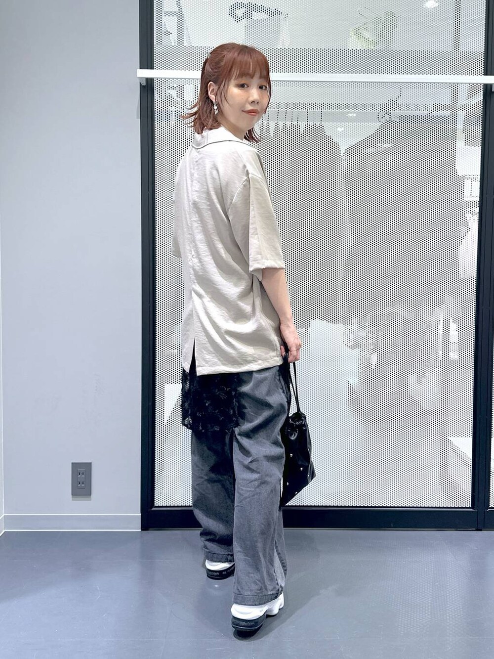 ブラック系のショルダーバッグ、ブラック系のデニムパンツ、ホワイト系のTシャツ/カットソーを着用したレディースの夏コーディネートの2枚目の写真