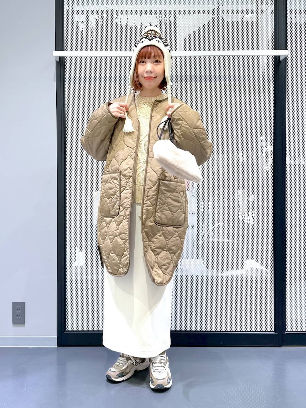 ブラウン系のスニーカー、ベージュ系のショルダーバッグ、グリーン系のナイロンジャケットを着用したレディースの冬コーディネートの5枚目の写真