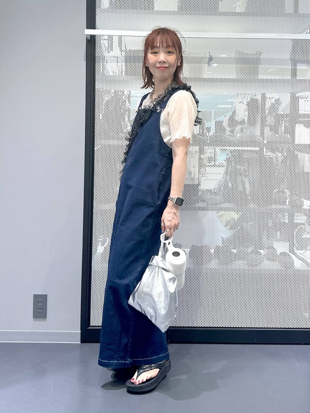 ブルー系のジャンパースカート、ブラック系のサンダル、ベージュ系のTシャツ/カットソーを着用したレディースの夏コーディネートの2枚目の写真