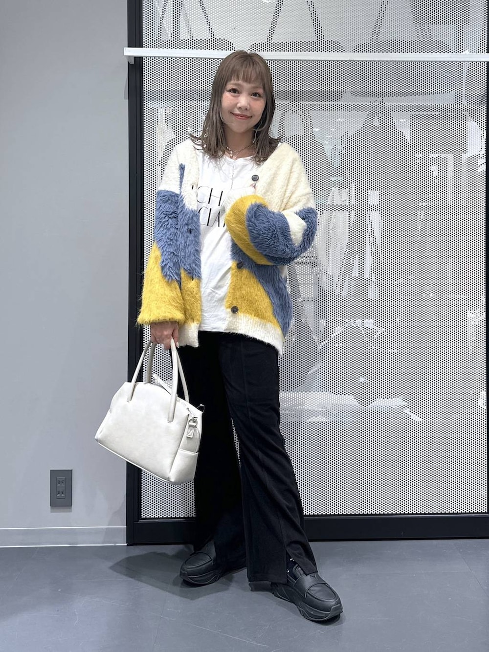 グレー系のボストンバッグ、イエロー系のカーディガン/ボレロ、ホワイト系のTシャツ/カットソーを着用したレディースの秋コーディネートの2枚目の写真