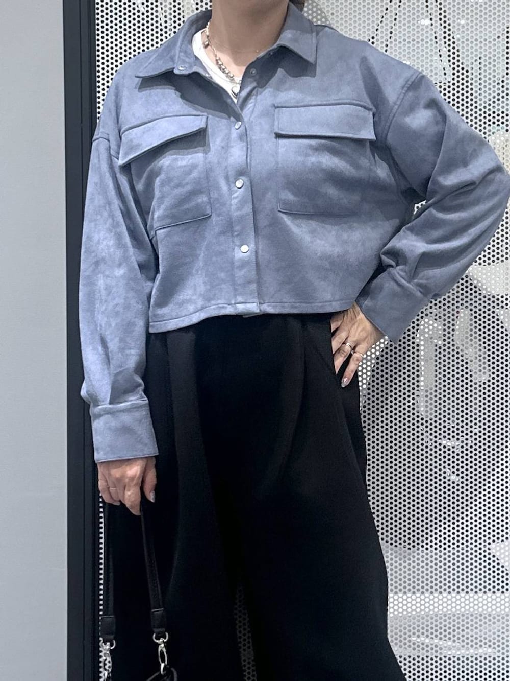 ホワイト系のタンクトップ、ブラック系のショルダーバッグ、ブラック系のスウェットパンツを着用したレディースの秋コーディネートの3枚目の写真