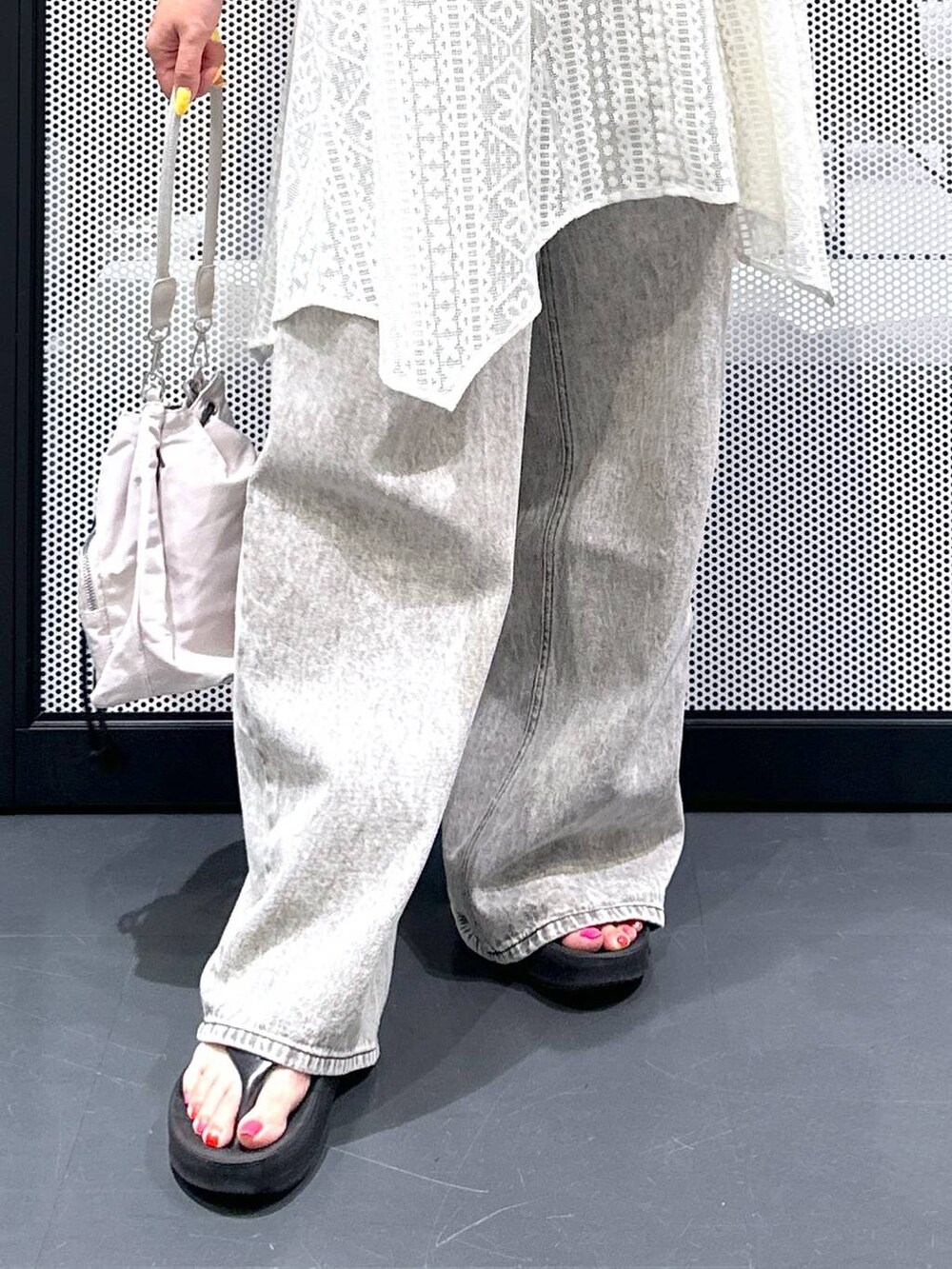 グレー系のデニムパンツ、ブラック系のサンダル、ホワイト系のショルダーバッグを着用したレディースの夏コーディネートの3枚目の写真