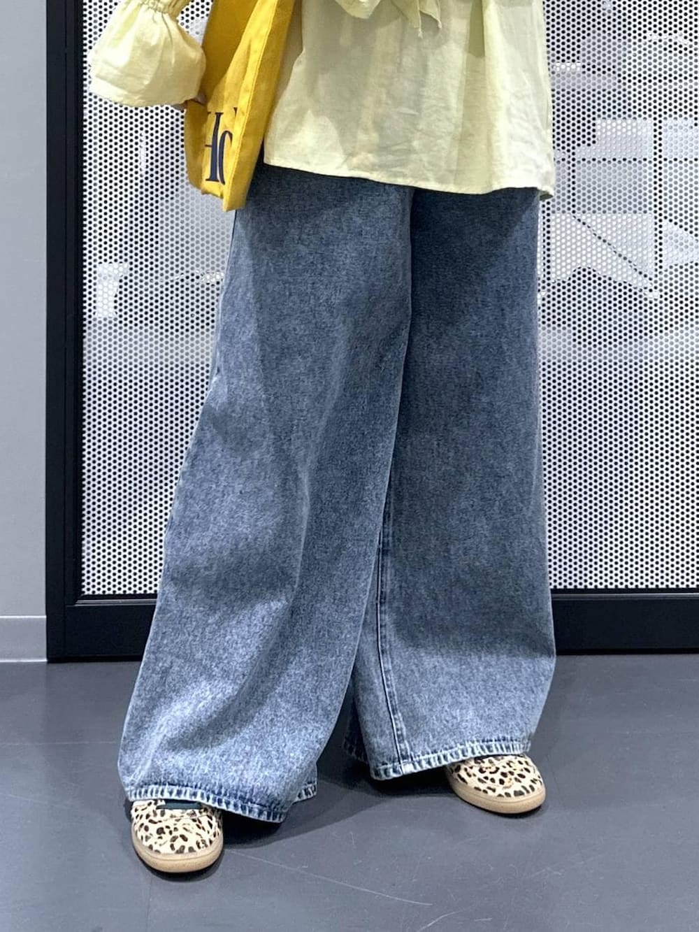 イエロー系のトートバッグ、ブルー系のデニムパンツ、ベージュ系のスニーカーを着用したレディースの春コーディネートの5枚目の写真