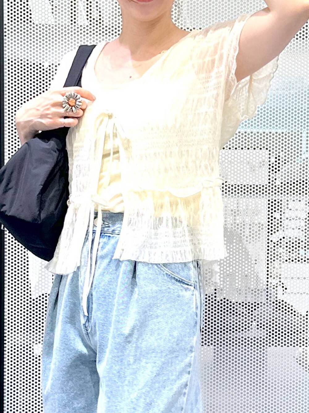 ブルー系のデニムパンツ、ブラック系のハンドバッグ、ベージュ系のサンダルを着用したレディースの夏コーディネートの5枚目の写真