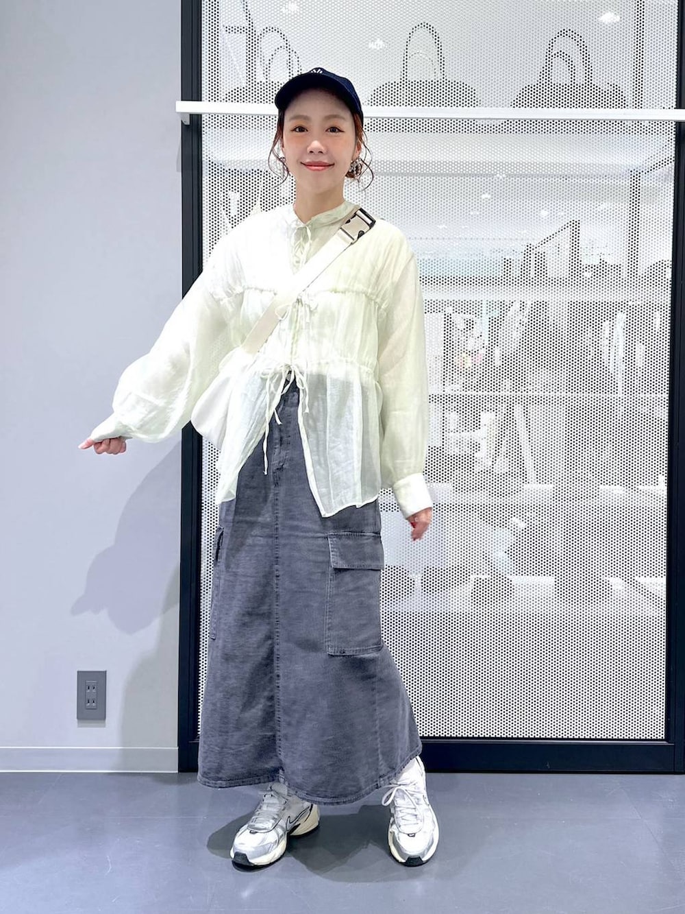 グレー系のデニムスカート、ホワイト系のTシャツ/カットソー、ホワイト系のショルダーバッグを着用したレディースの春コーディネートの2枚目の写真