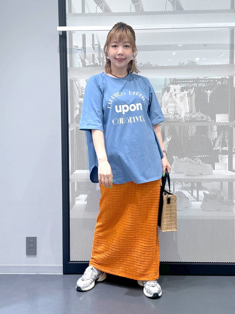 ベージュ系のショルダーバッグ、オレンジ系のスカート、ブルー系のTシャツ/カットソーを着用したレディースの春コーディネートの2枚目の写真