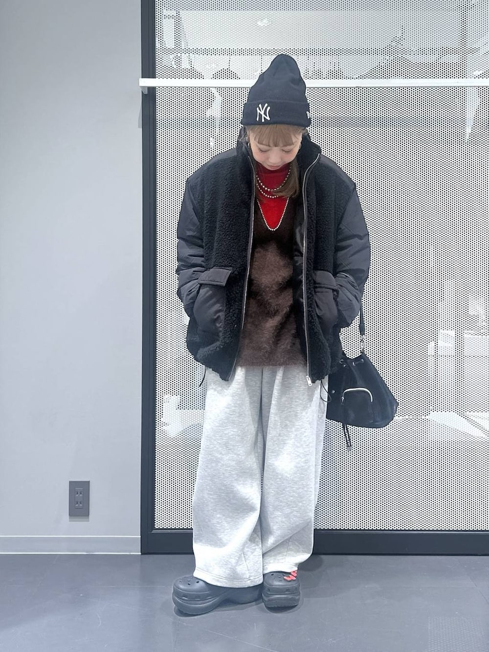 ブラック系のブルゾン、ブラック系のショルダーバッグ、ブラウン系のベストを着用したレディースの冬コーディネートの3枚目の写真