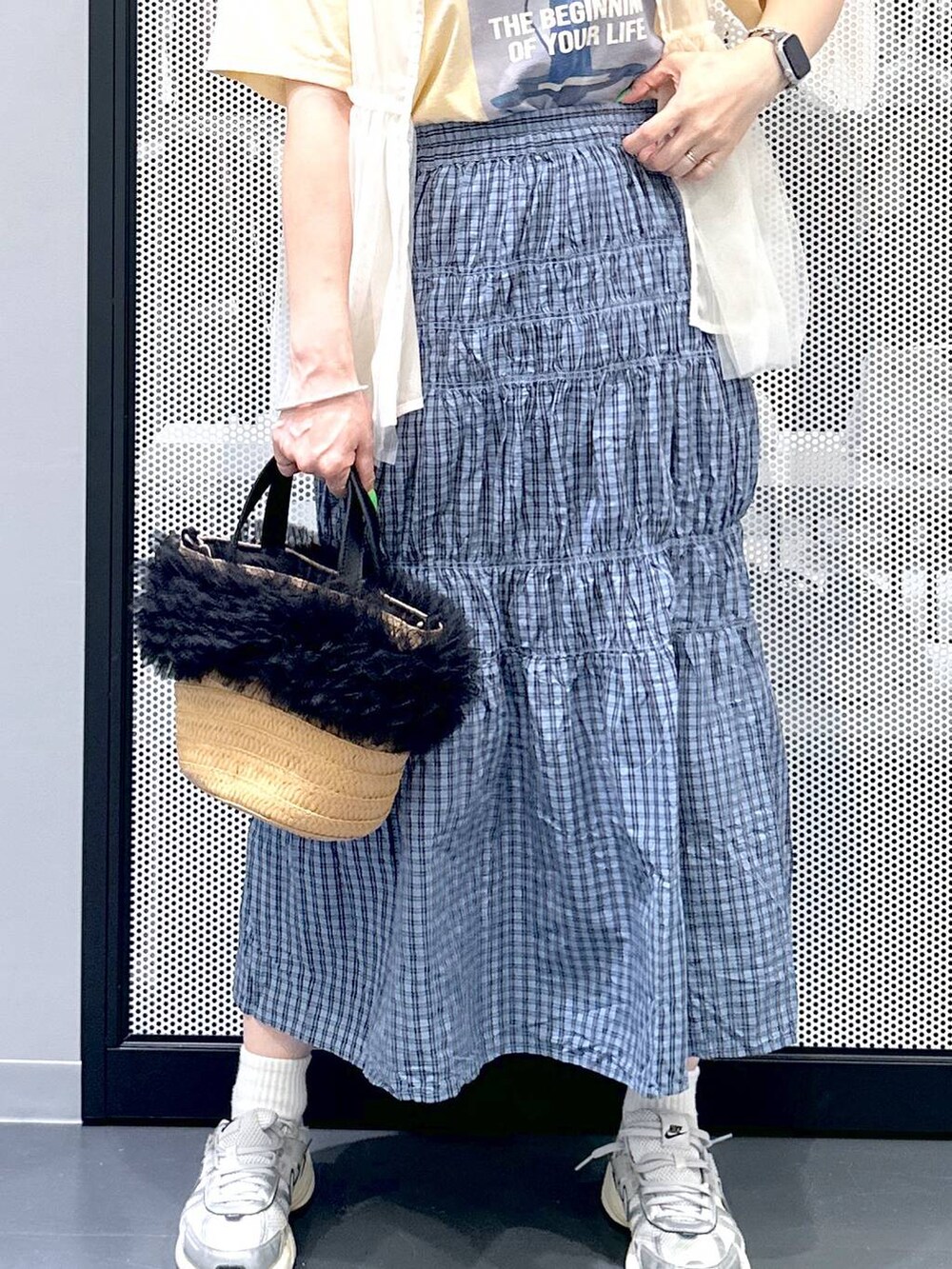 ベージュ系のショルダーバッグ、イエロー系のTシャツ/カットソー、ブルー系のスカートを着用したレディースの春コーディネートの6枚目の写真