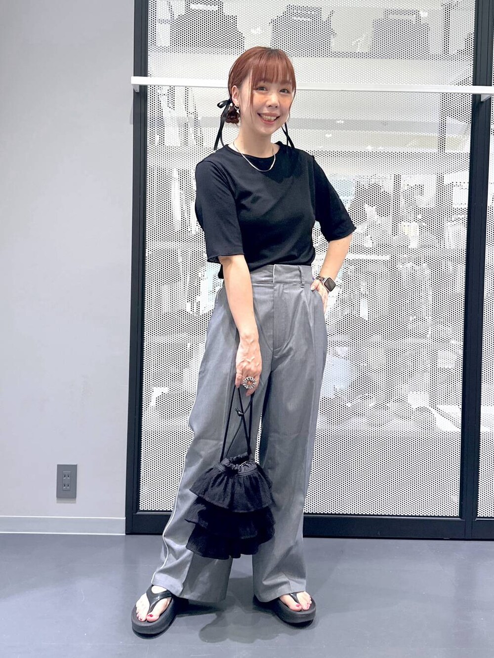 ブラック系のTシャツ/カットソー、グレー系のスラックス、ブラック系のサンダルを着用したレディースの夏コーディネートの2枚目の写真